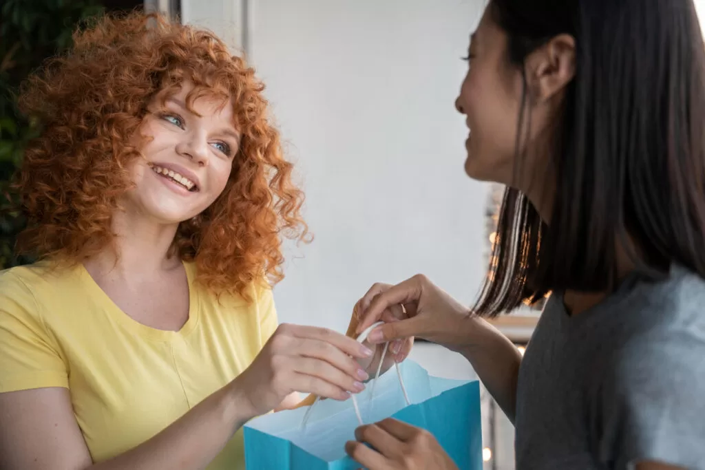 Marketing de experiência: vendedora entregando sacola de compras para cliente.