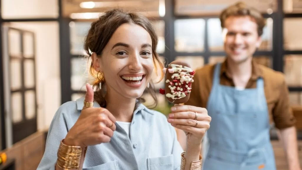 formas de fidelizar o cliente: cliente com sorvete na mão e vendedor atras e ela fazendo sinal de "joinha" com a mão.