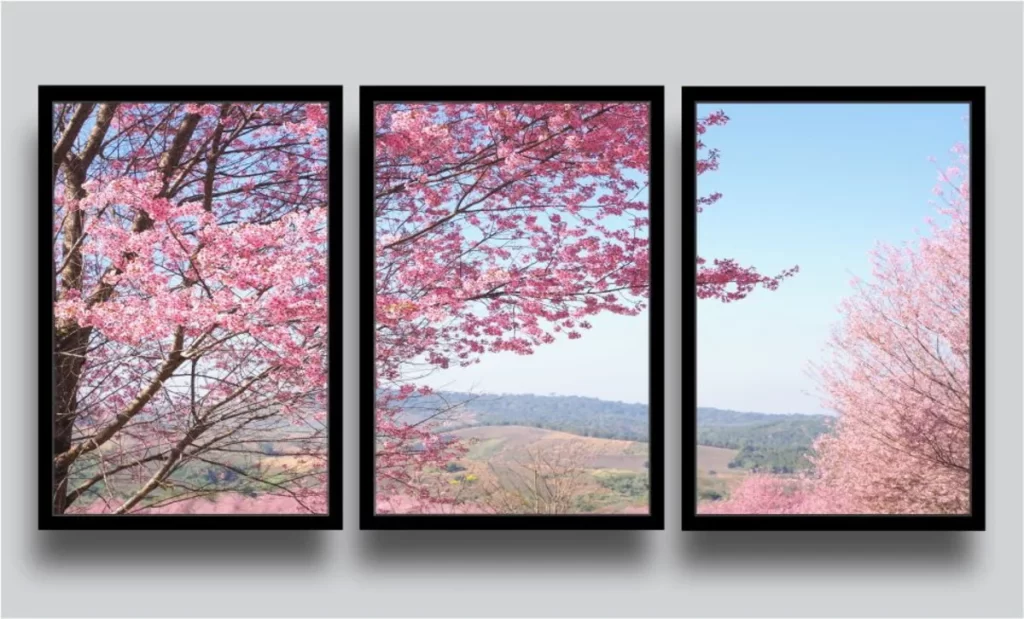 Três quadros em parede criando uma imagem de uma arvore de cerejeira com uma paisagem atrás.